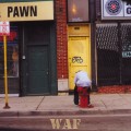 a Chicago street scene of a man sitting on a fire hydrant near a pawn shop